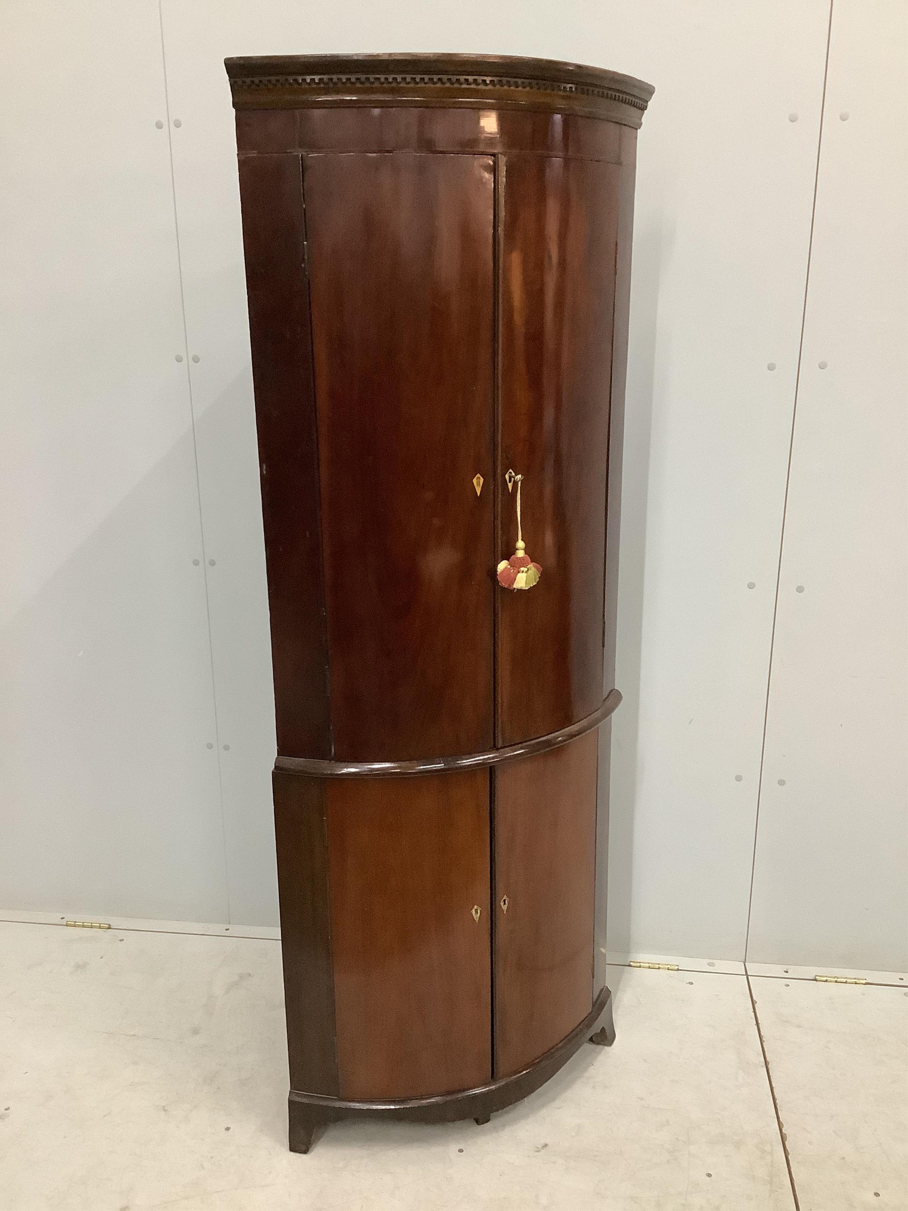 A George III mahogany bow front corner cupboard on later base, width 70cm, depth 46cm, height 179cm. Condition - fair